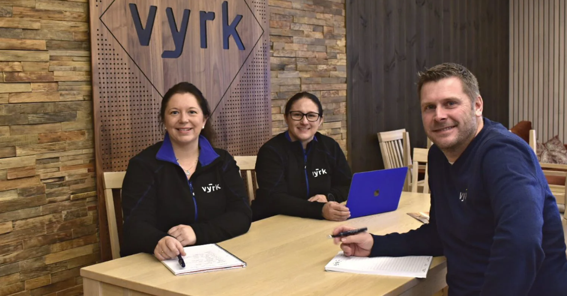 Vyrk-ansatte foran Vyrk-logo.