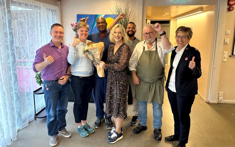 Bildet viser en gruppe blide mennesker som står oppstil tog smiler mot kamera.