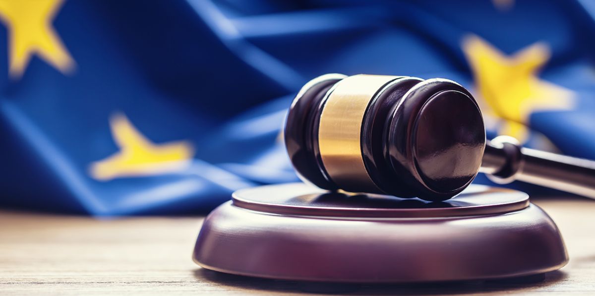 Bilde av en lov-hammer på et bord, og med et EU-flagg i bakgrunnen