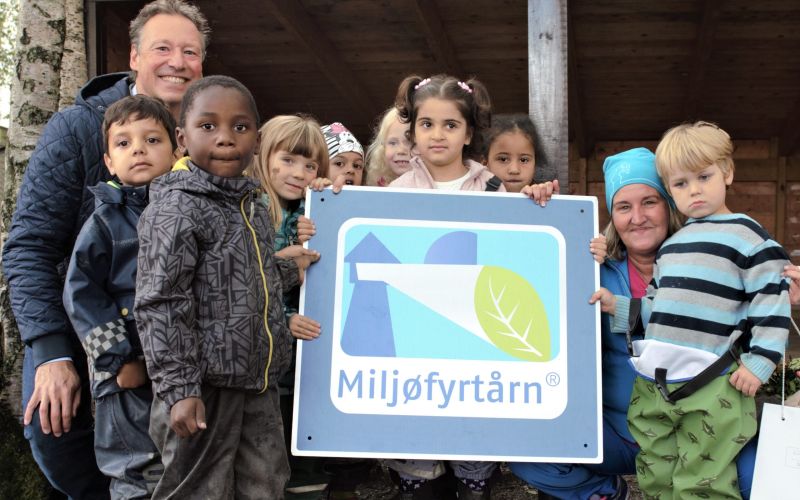 Barn i barnehagen står oppstilt og holder frem Miljøfyrtårn-diplom