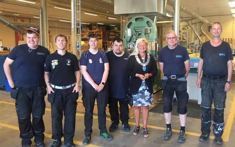 6 ar6 arbeidere står oppstilt med ordfører for kamera i arbeidslokaler