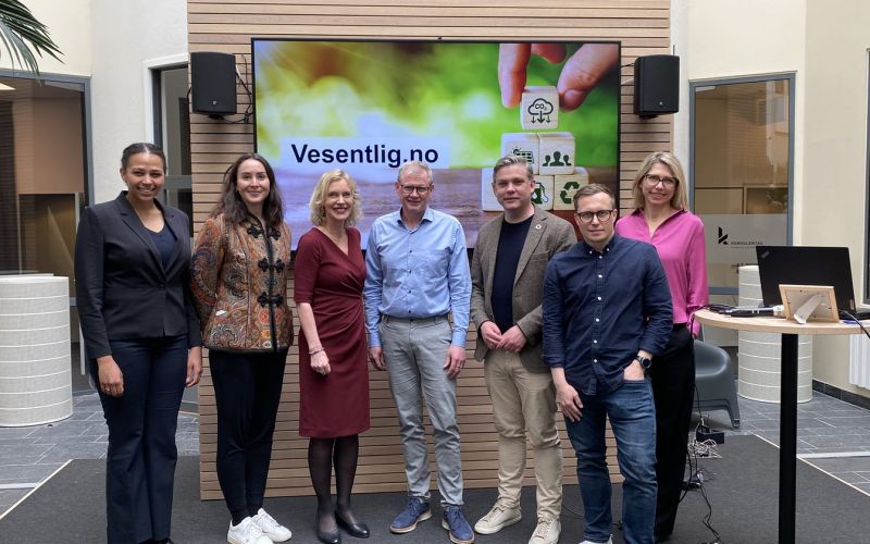 Innledere fra lanseringen står oppstilt foran en skjerm.