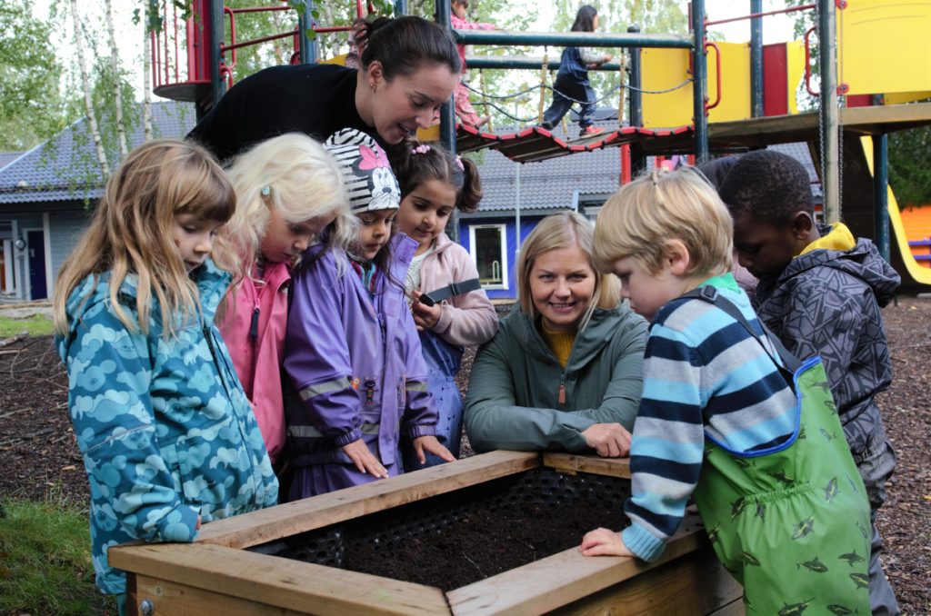 Barn og voksne står og ser på jordkasse