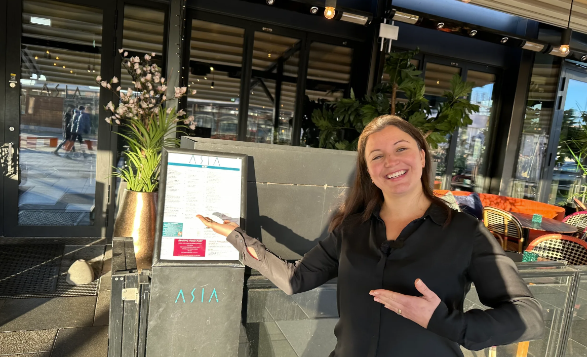 Pernille Koppang, driftssjef på restaurant ASIA, viser menyen på utsiden av restauranten.